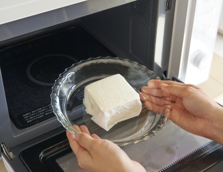 豆腐をキッチンペーパーに包んで電子レンジで２分加熱する様子