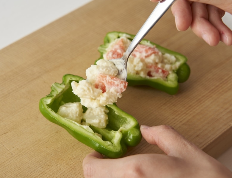 半分に切ったピーマンにポテトサラダを詰める様子